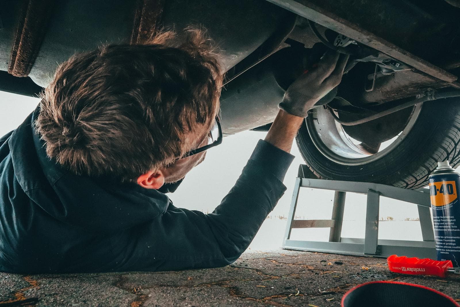 Technician working underneath a vehicle on a service lift.