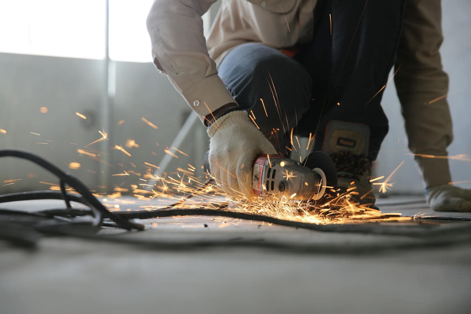 Angle grinder cutting metal with sparks flying in a workshop.